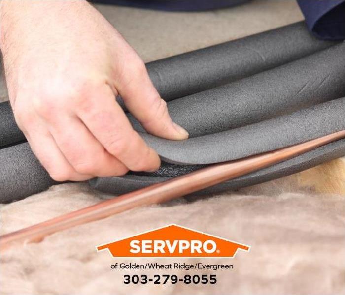 A person is wrapping insulation around copper pipes to prevent them from freezing.
